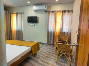a bedroom with a bed and a chair and a tv at Mangrove Village Inn in Kāsarkod