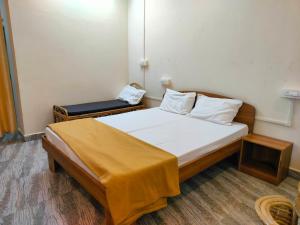 a bedroom with a bed with a yellow blanket on it at Mangrove Village Inn in Kāsarkod +4 photos