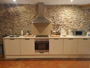 a kitchen with white cabinets and a stone wall at L'Era de Can Ribes Tor in Tor