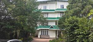 a large white building with a green roof at Apsara Guest House, Peaceful Area in Central Shillong in Shillong