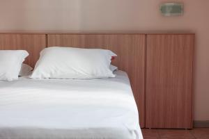 ein Bett mit hölzernem Kopfteil, weißen Laken und Kissen in der Unterkunft Hotel Açores in Balneário Camboriú + 4 Fotos