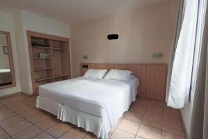 ein Schlafzimmer mit einem weißen Bett in einem Zimmer in der Unterkunft Hotel Açores in Balneário Camboriú