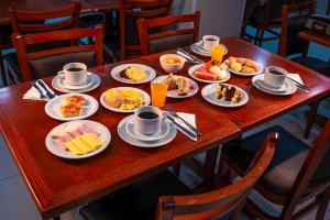 ein Holztisch mit Tellern voller Essen darauf in der Unterkunft Hotel Açores in Balneário Camboriú