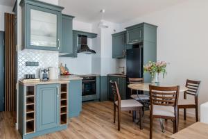 a kitchen with blue cabinets and a table and chairs at Zegrze Lake Apartament VIRIDIAN z widokiem na jezioro, tarasem i parkingiem in Zegrze