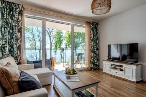 a living room with a couch and a tv at Zegrze Lake Apartament VIRIDIAN z widokiem na jezioro, tarasem i parkingiem in Zegrze