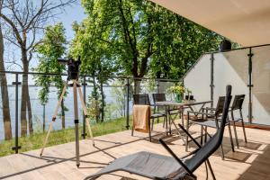 a camera on a tripod on a deck with a table and chairs at Zegrze Lake Apartament VIRIDIAN z widokiem na jezioro, tarasem i parkingiem in Zegrze
