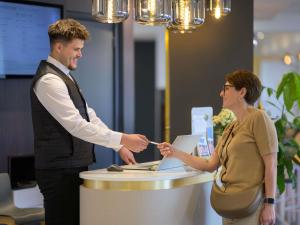 a man handing a woman a credit card at Mercure Honfleur in Honfleur