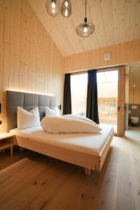 a bedroom with a large bed and a large window at Preindlerhof Farmloft in Valle Di Casies