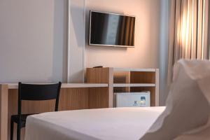 a room with a bed and a tv on a wall at Hotel Sagres Praia in Balneário Camboriú