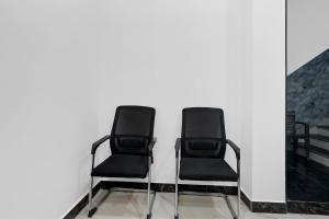 two black chairs sitting next to a white wall at Super Hotel O Antilia in Gorakhpur