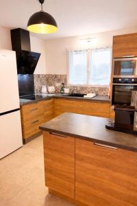 a kitchen with wooden cabinets and a white refrigerator at Charmante maison neuve proche Ocean in Léon