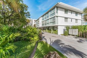 a white building with palm trees in front of a street at Beach Haus Key Biscayne Contemporary Apartments in Miami