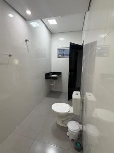 a white bathroom with a toilet and a sink at Lotus in Gurupi +10 photos