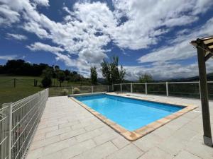 a swimming pool on a patio with a fence at Le Gite Cazette in Ance