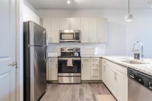 a kitchen with white cabinets and a stainless steel refrigerator at Warm, Inviting 2BD Apt In Matthews in Charlotte