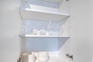 a shelf filled with wine glasses in a kitchen at Warm, Inviting 2BD Apt In Matthews in Charlotte