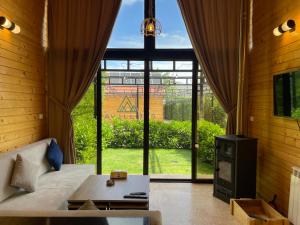 a living room with a couch and a tv and a window at Les Pavillons D'Ehden in Ehden