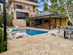 a pool with chairs and tables and a house at Les Pavillons D'Ehden in Ehden
