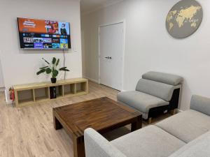 a living room with a couch and a table at Spacious New Home for 12 Guests in Campbelltown South