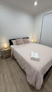 a bedroom with a large bed with two towels on it at Spacious New Home for 12 Guests in Campbelltown South