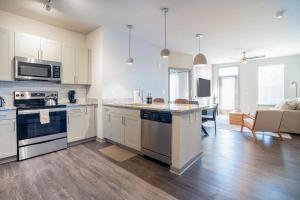 a kitchen with white appliances and a living room at Stylish, Comfortable 2BD Abode near DT Matthews in Charlotte