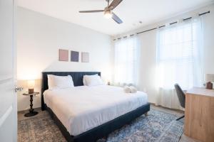 a bedroom with a bed with white sheets and a ceiling fan at Stylish, Comfortable 2BD Abode near DT Matthews in Charlotte