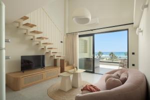 a living room with a couch and a tv and a staircase at Paligremnos Infinity - Adults only in Plakias