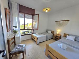 a bedroom with two beds and a chair and a window at Apartamento La Hojarada 20809 in Argoños