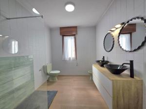 a bathroom with two sinks and a toilet and a mirror at Apartamento La Hojarada 20809 in Argoños +18 photos