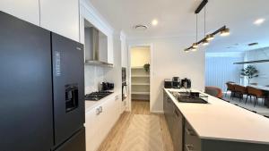 a kitchen with black appliances and a dining room at Spacious New Home for 12 Guests in Campbelltown South