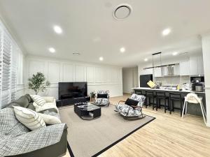 a living room with a couch and a kitchen at Spacious New Home for 12 Guests in Campbelltown South