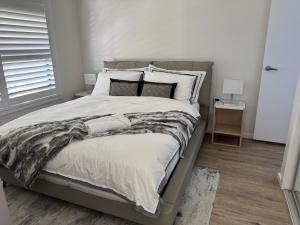 a bedroom with a large bed with white sheets and pillows at Spacious New Home for 12 Guests in Campbelltown South