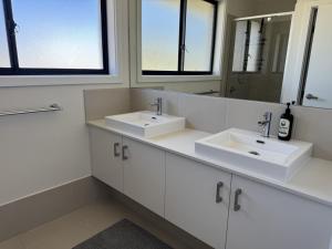 a bathroom with two sinks and two mirrors at Spacious New Home for 12 Guests in Campbelltown South +27 photos