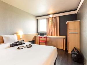 a hotel room with a bed and a desk and a window at ibis Pau Lescar in Lescar +42 photos