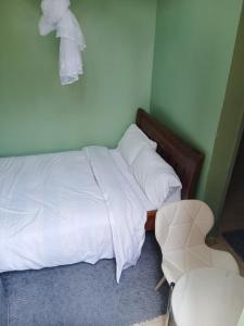 a bedroom with a bed with white sheets and a chair at Amazing Grace Home - Oyugis studio in Oyugis +7 photos