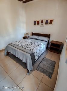 a bedroom with a large bed and a rug at Chalé Refúgio Casarão in Passa Quatro