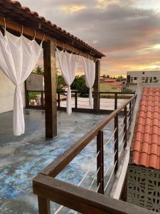 a balcony with white curtains and a fence at Casa 3 amores PREÁ, vento, charme, piscina e 2 quartos in Prea