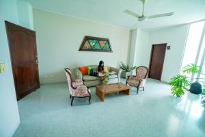 a woman sitting on a couch in a living room at Hotel Tropical in Corozal