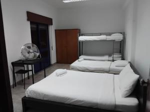 a bedroom with two beds and a desk with a fan at Come Inn Costa da Caparica in Costa da Caparica +8 photos