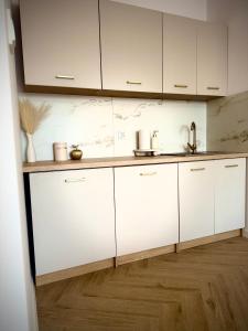 a kitchen with white cabinets and a wooden floor at Kaszmirowy Apartament in Mrągowo