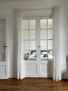 a white room with a bed and a window at Le Clair Bellifontain in Fontainebleau