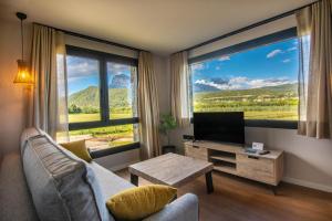 a living room with a couch and a tv and large windows at Casas Green Ordesa in Aínsa