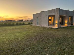 a small concrete house in a field with the sunset at Quinta Narbaiz in Estación Nueve de Julio Sur