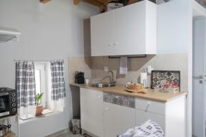 a kitchen with white cabinets and a sink at Πέτρινο Αλώνι in Panayía
