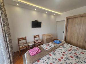 a bedroom with a bed and two chairs and a tv at Rooms Vlaovic in Herceg-Novi