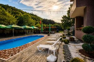 a pool with benches and umbrellas next to a building at Wooden Cabin 1 with Pool Access - Bate Bole Resort in Ohrid