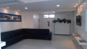 a waiting room with a black couch in a building at Hotel Imperador in Jaraguá