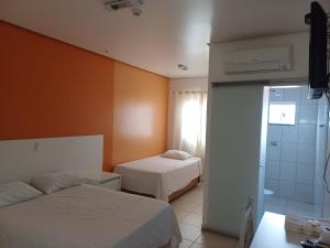 a hotel room with two beds and a shower at Hotel Imperador in Jaraguá