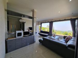 a living room with a couch and a tv at Villa Mahlin 3 kamar in Tutugan