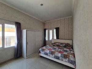 a bedroom with a bed and a large window at Villa Mahlin 3 kamar in Tutugan